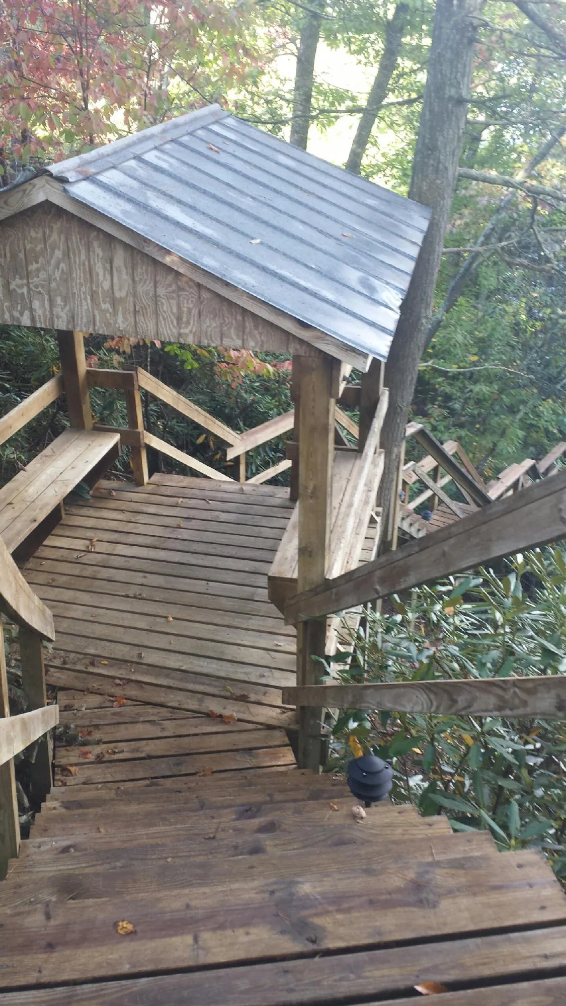 Metal roofed shelter over wooden steps on a wooded walkway — Skylight Repair & Installation work by our crew in Akron